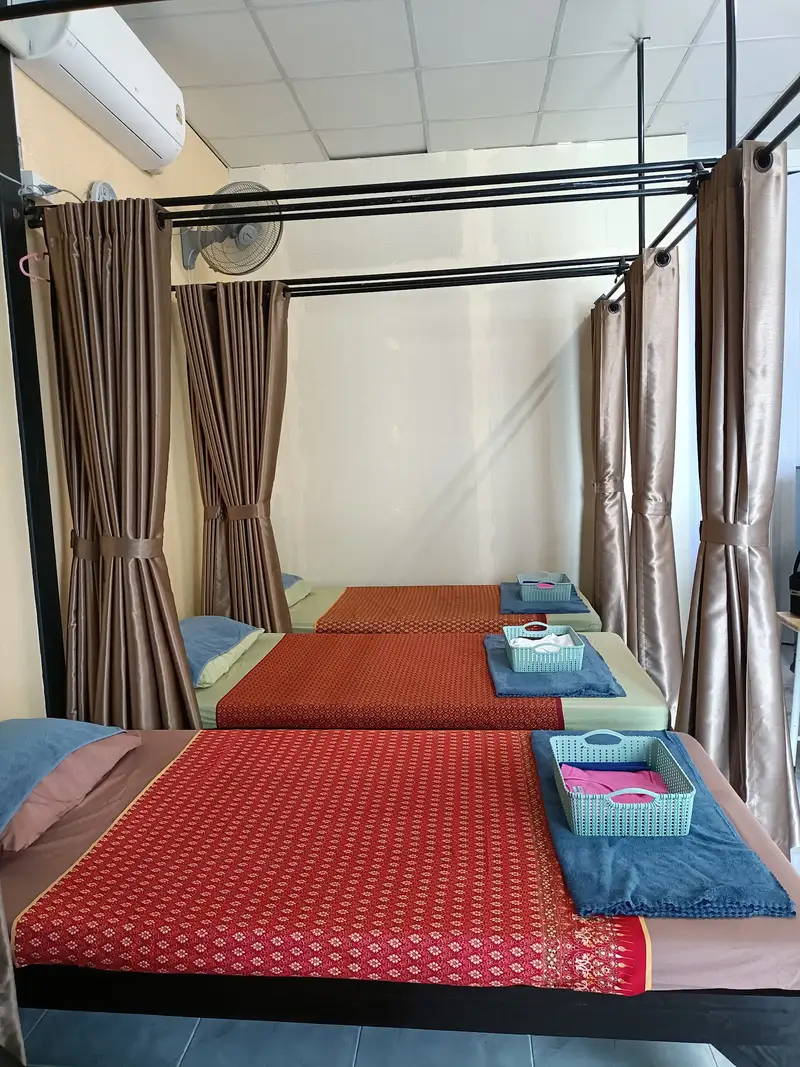 เตียงนวดผ้าลายไทยสีแดงพร้อมผ้าเช็ดตัว / Massage beds with red Thai-pattern covers and towels
